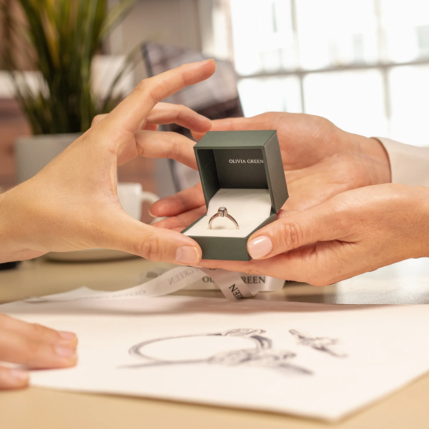 A customer smiling in the Olivia Green York showroom with a ring box