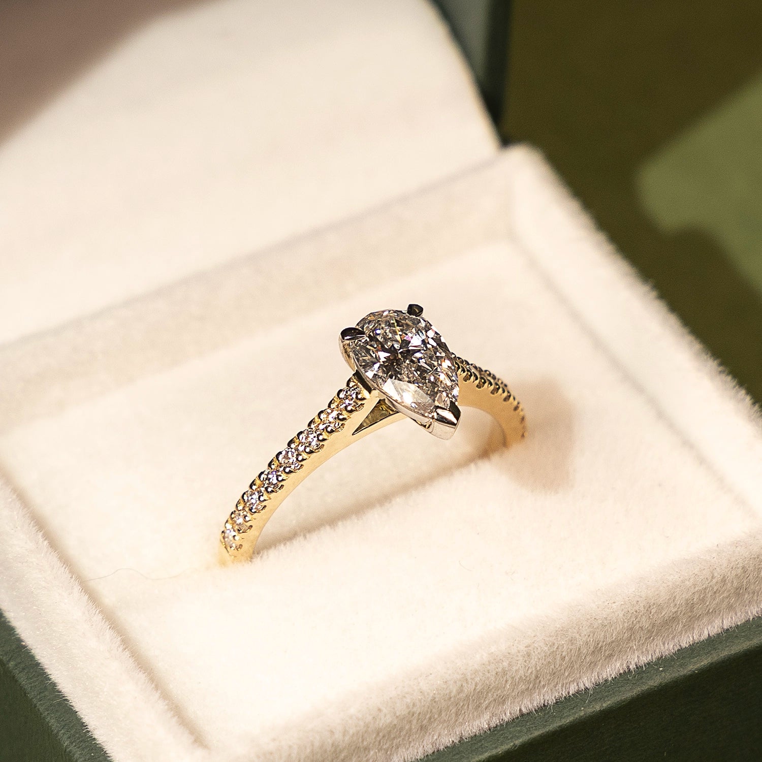 Diamond ring with gold band on a white cushion in a jewelry box